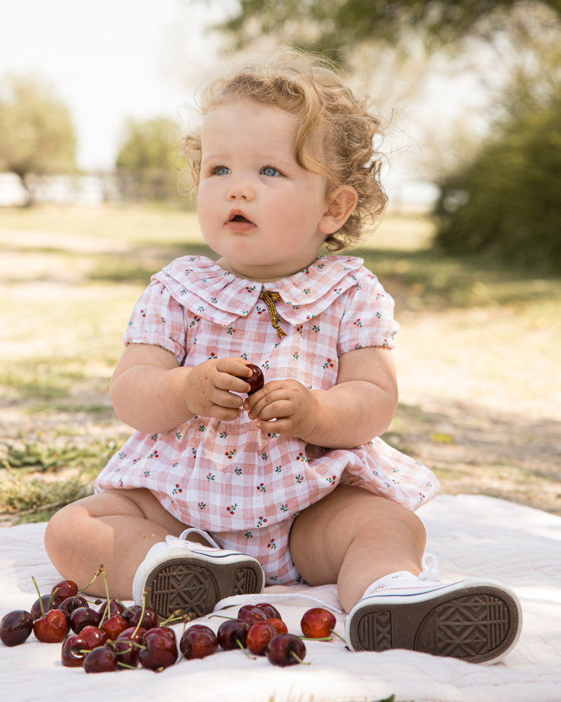 Romper for baby dress in gingham print with flowers. Ruffle neck and gold bow detail. Cosmosophie