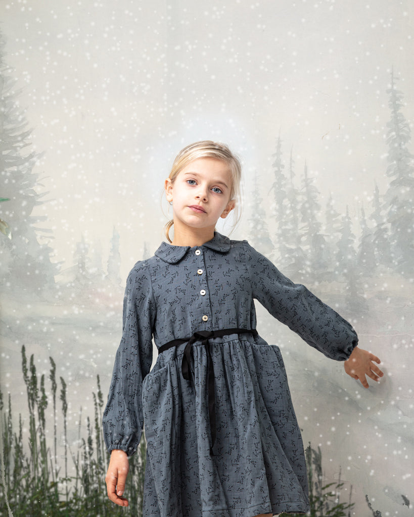 Front button dress with baby collar. You will love its blue double gauze fabric with a print of small black flowers. As details, it has a black ribbon that is tied at the waist.