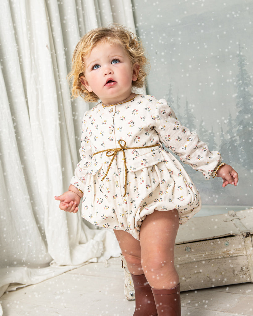Your baby will look beautiful in this floral print romper in blue, pink and mustard on an ecru background. You'll love the contrasting detail on the neck, its decorative pockets and its tie detail at the waist. Front button closure and between legs. Elasticated cuffs for greater comfort.