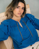 Blusa en algodon vaporoso azul cian con doble volante en el hombro y lazada en oro